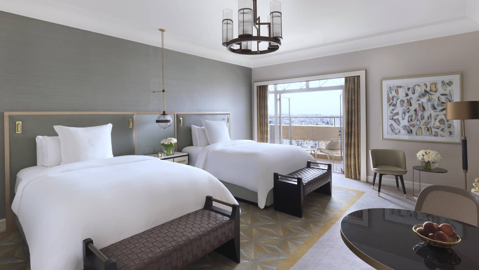 Royal Suite second bedroom featuring two queen beds, multiple seating areas and glass doors that open onto a private balcony