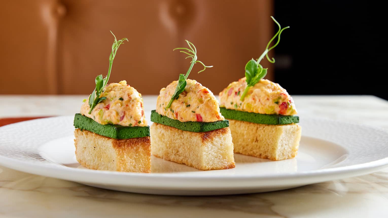 Three pieces Old Bay Lobster Salad atop Spinach Spread on Brioche Bread