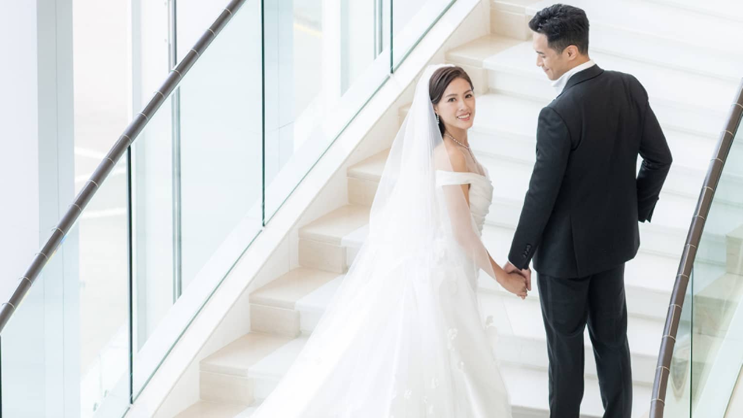 Bride and groom stand on stunning curved staircase at Four Seasons Hotel Hong Kong