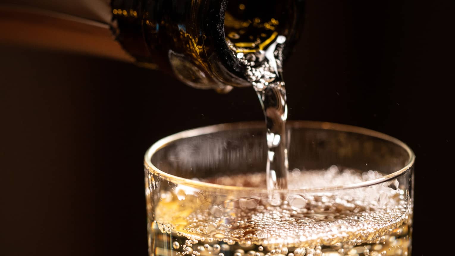 A bottle of wine being poured into a glass.