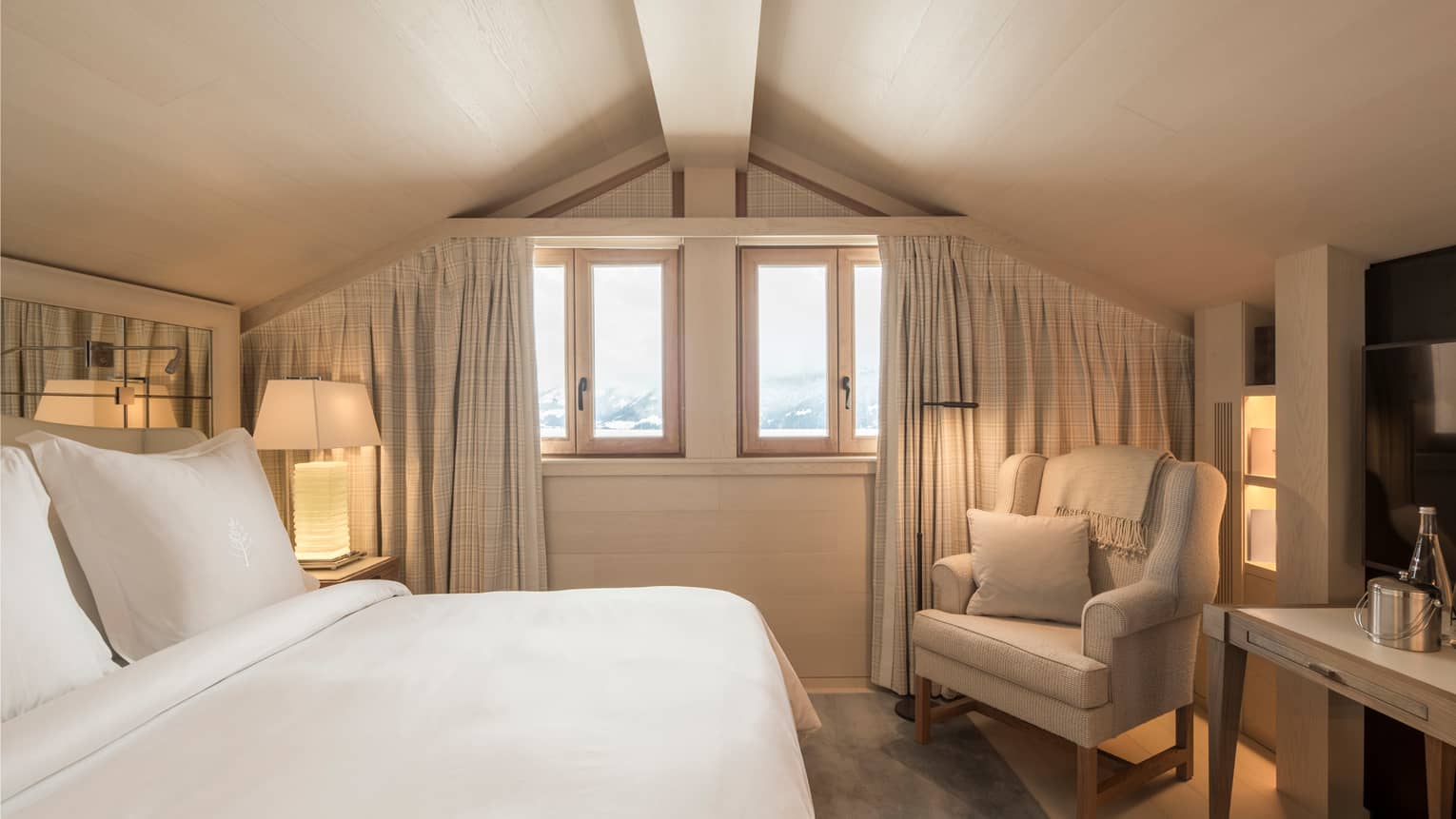 Superior Room bed, white lamp, armchair under sloped ceiling, small windows