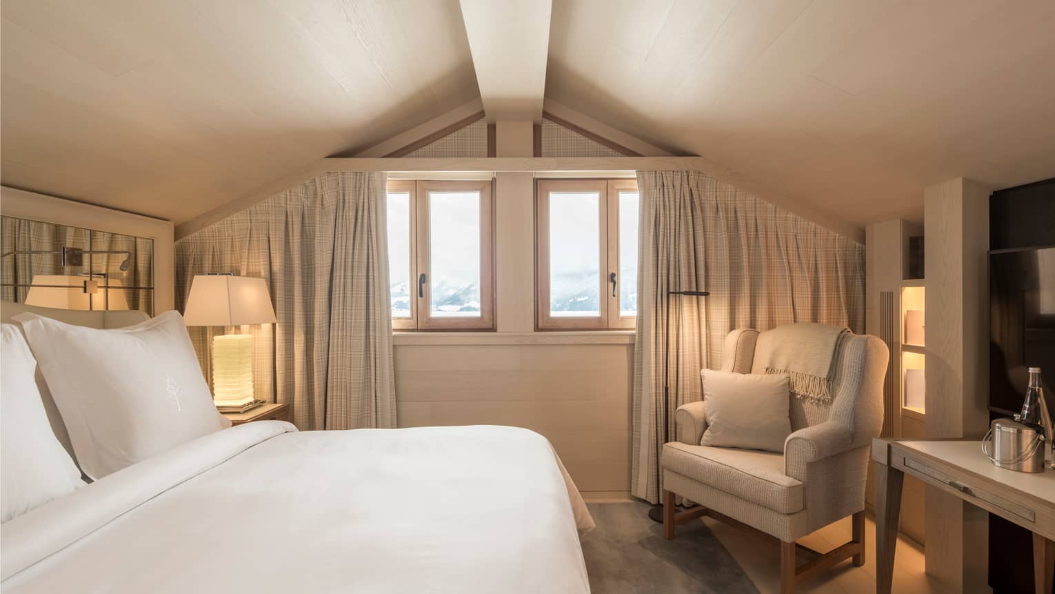 Superior Room bed, white lamp, armchair under sloped ceiling, small windows