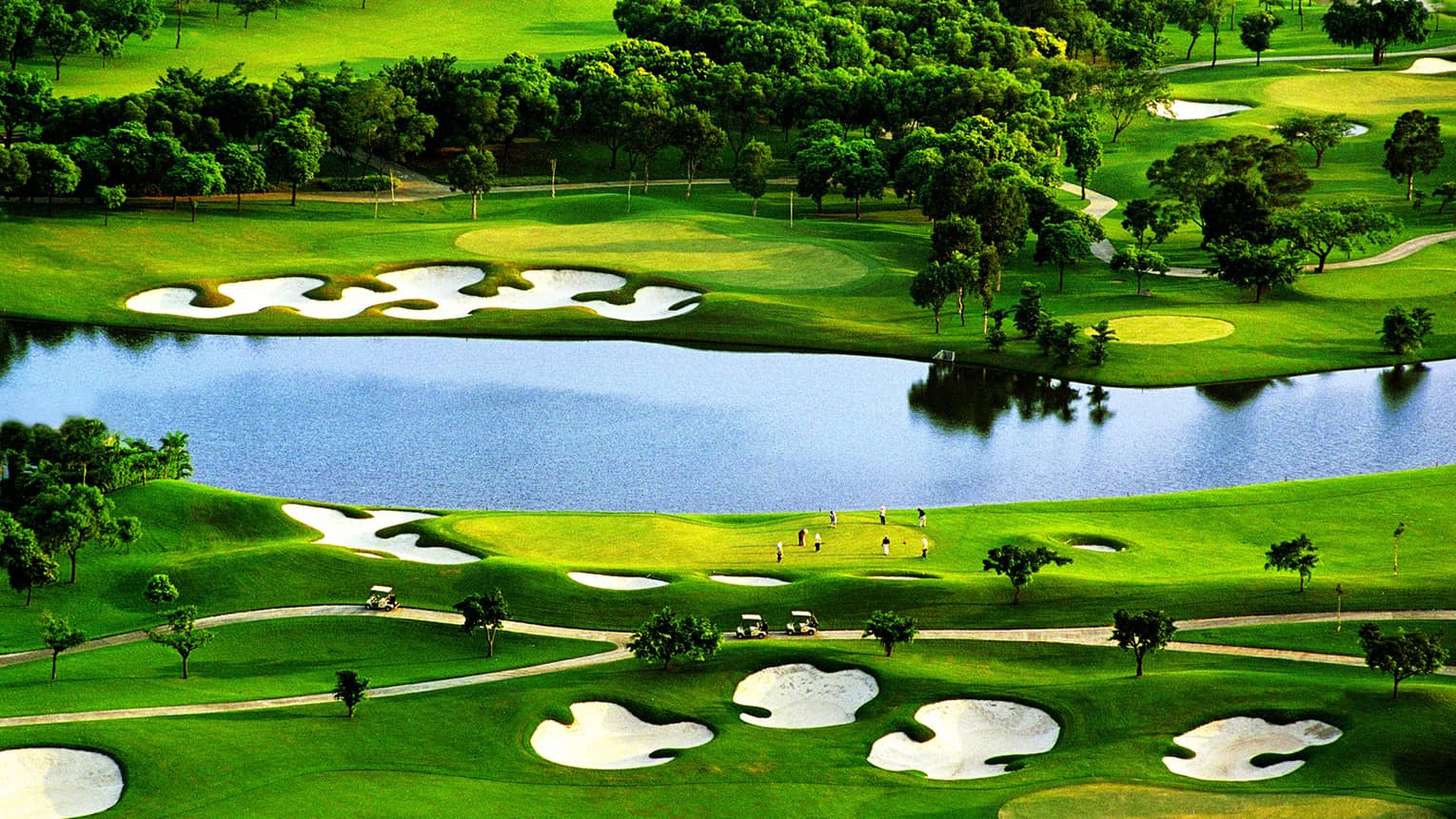 Golf greens with sand traps, large pond, trees