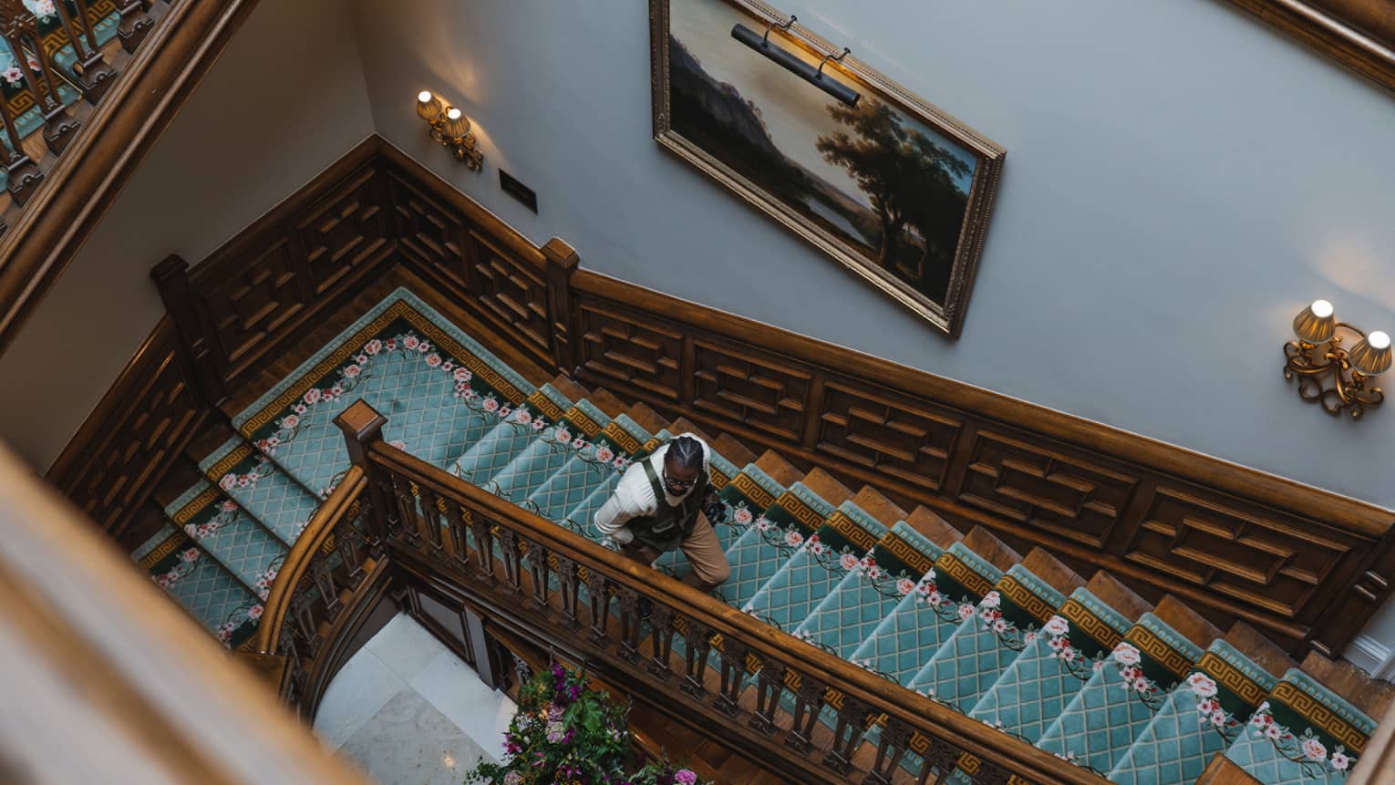 A rectangular wood spiral staircase with a teal blue runner