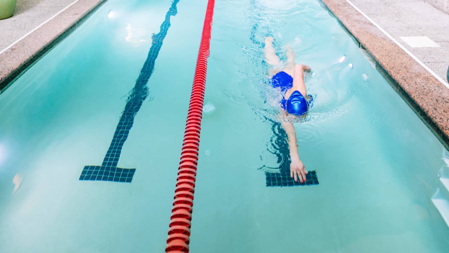 A woman swims laps in an olympic-sized pool
