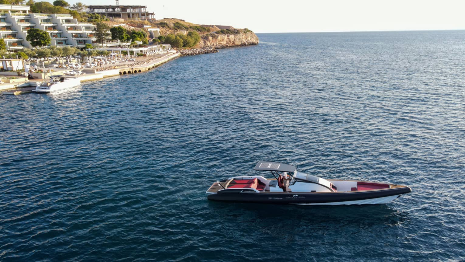 Small Greek-style yacht heading out toward open water from Astir Palace Hotel dock.