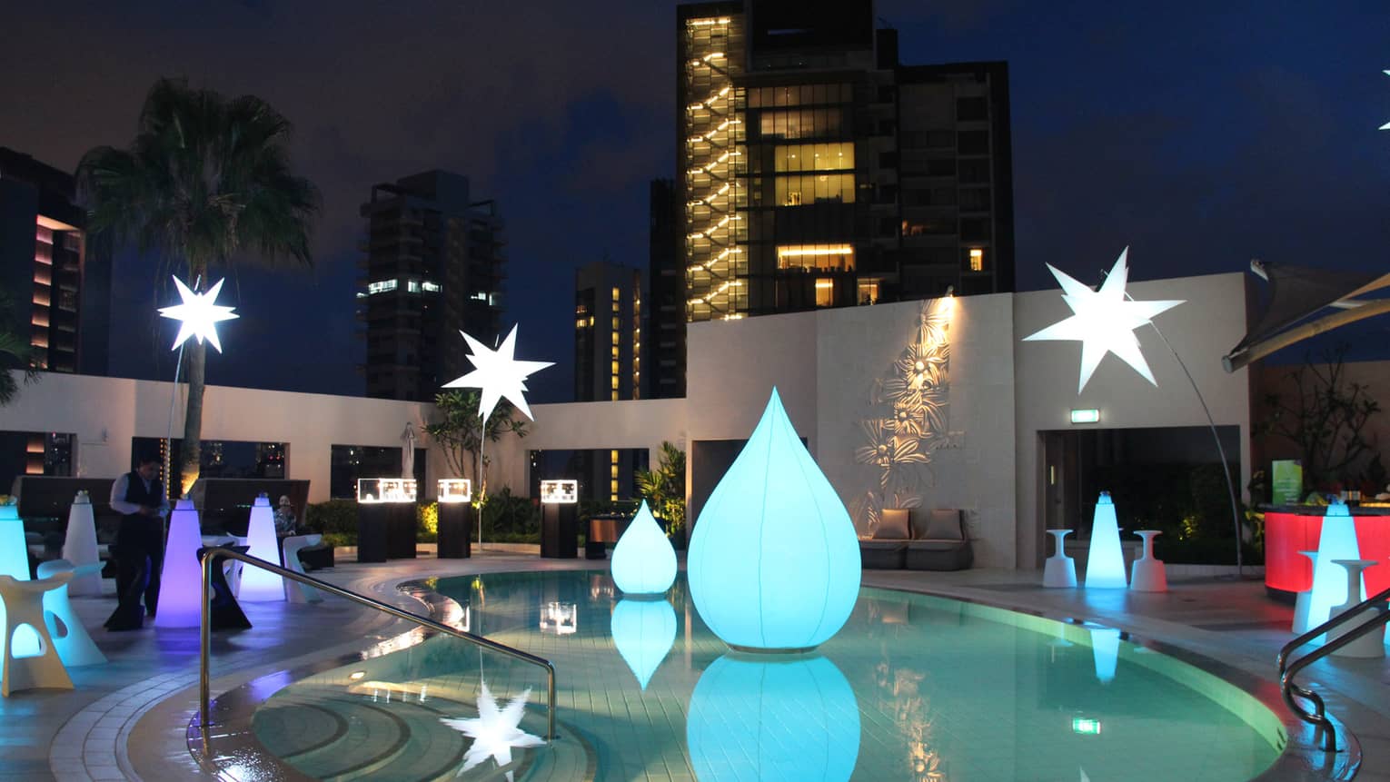 ,An outdoor pool decorated with various floating light-up balloons