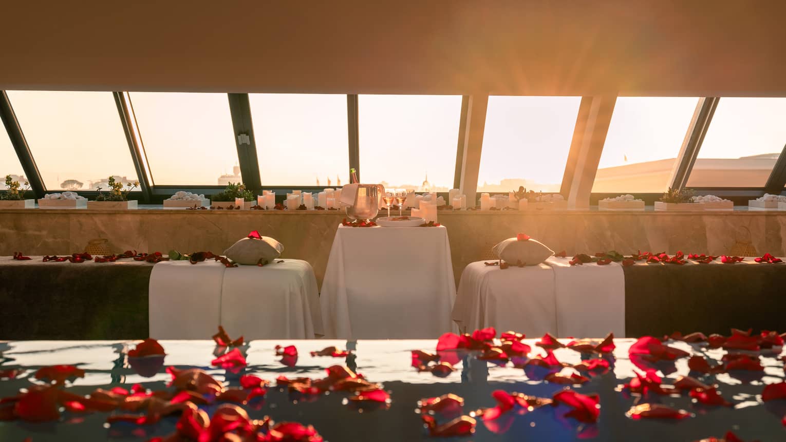 Spa pool sprinkled with red rose petals and couples spa tables poolside with skylight views