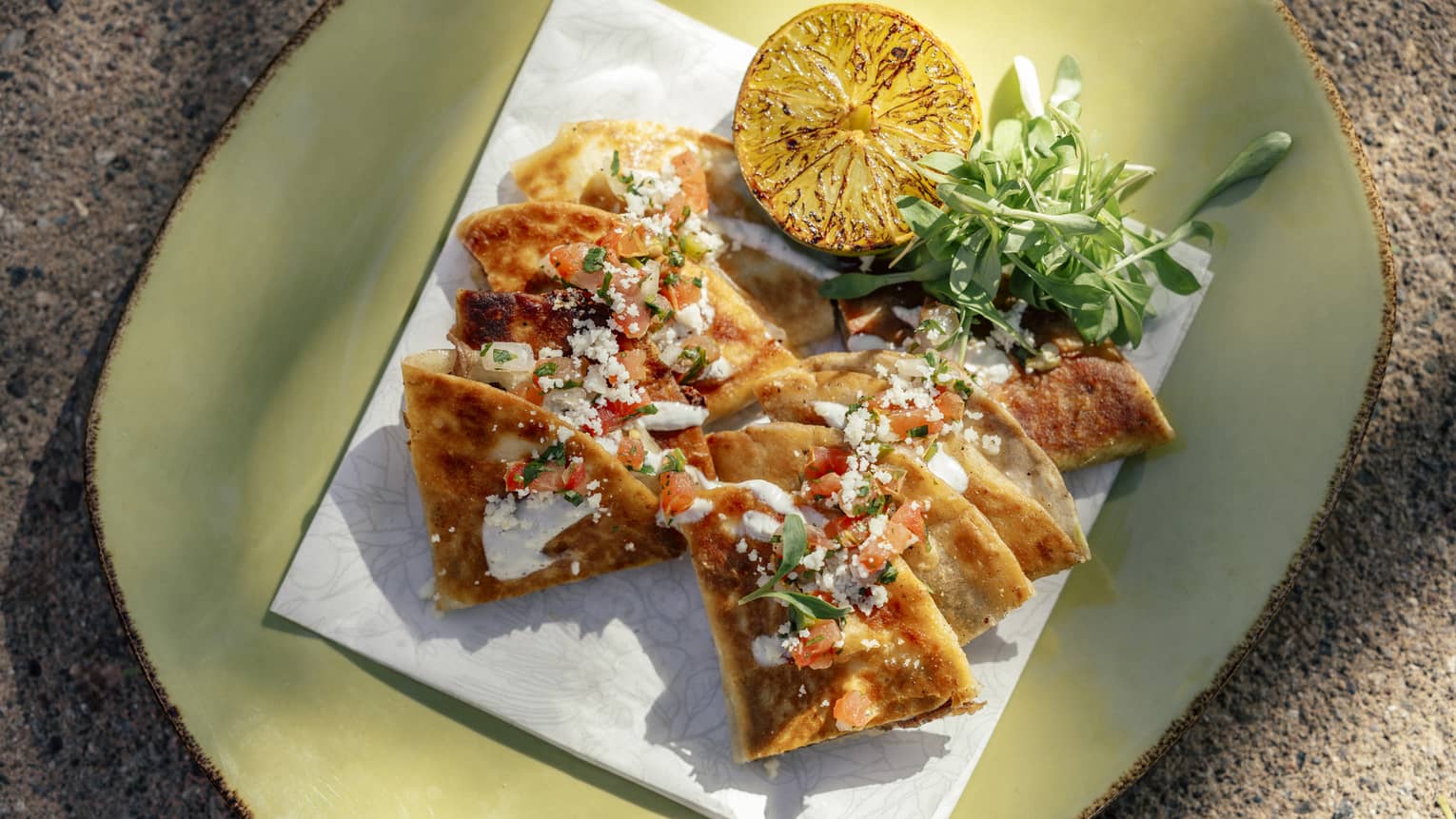 Quesadilla cut into wedges with greens and grilled citrus