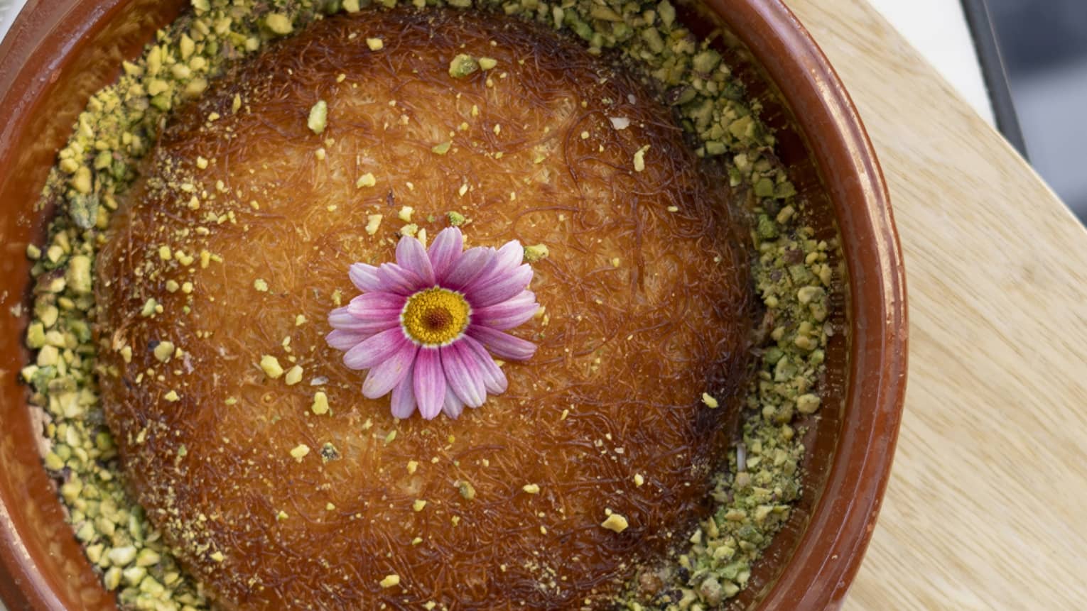 Traditional kunafeh served in a brown stoneware bowl