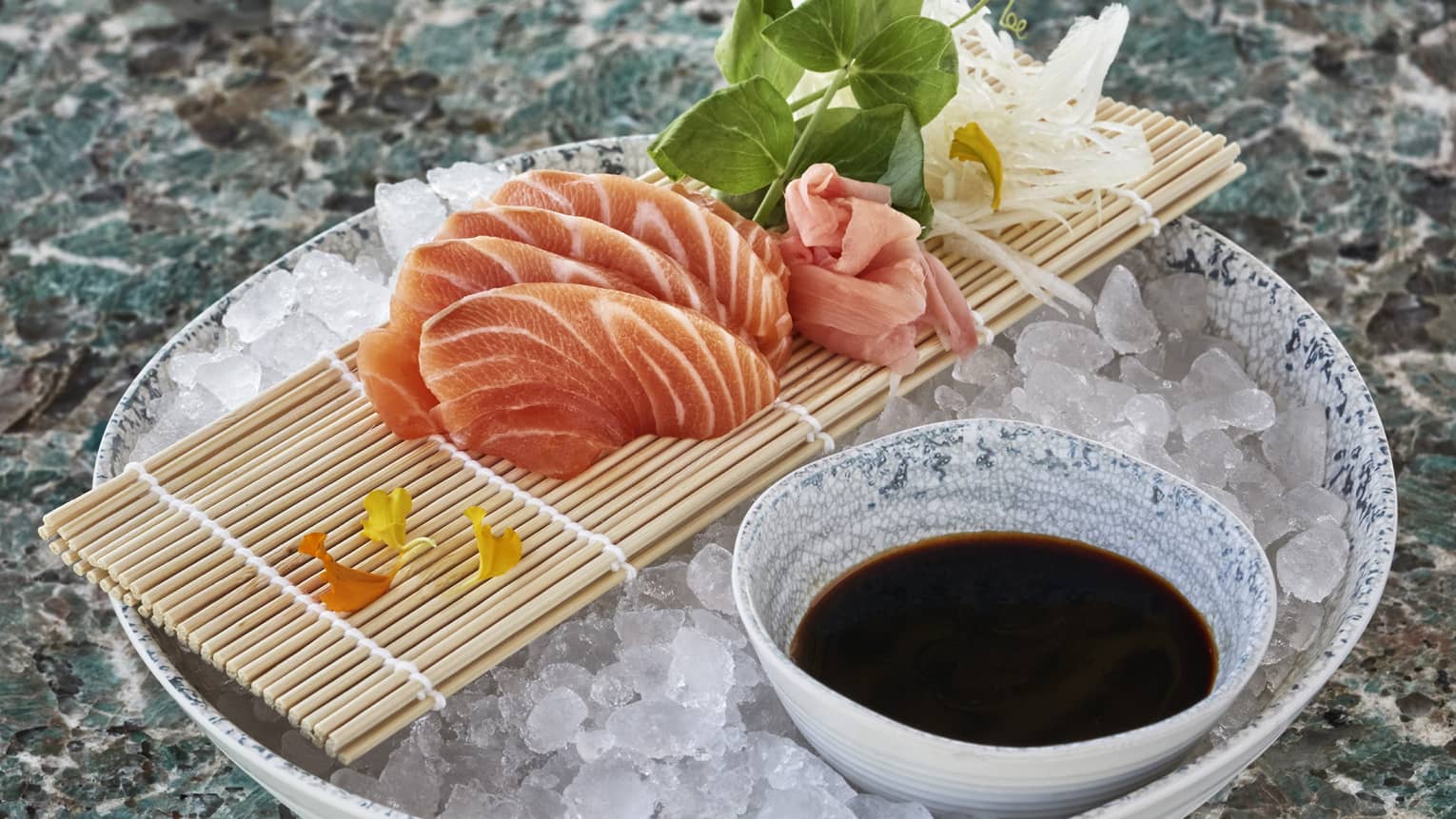 Sliced raw fish over ice next to a small bowl of soy sauce.