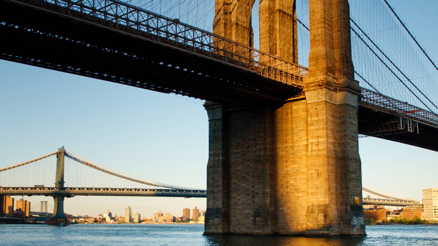 The Brooklyn Bridge at sunset on the water 