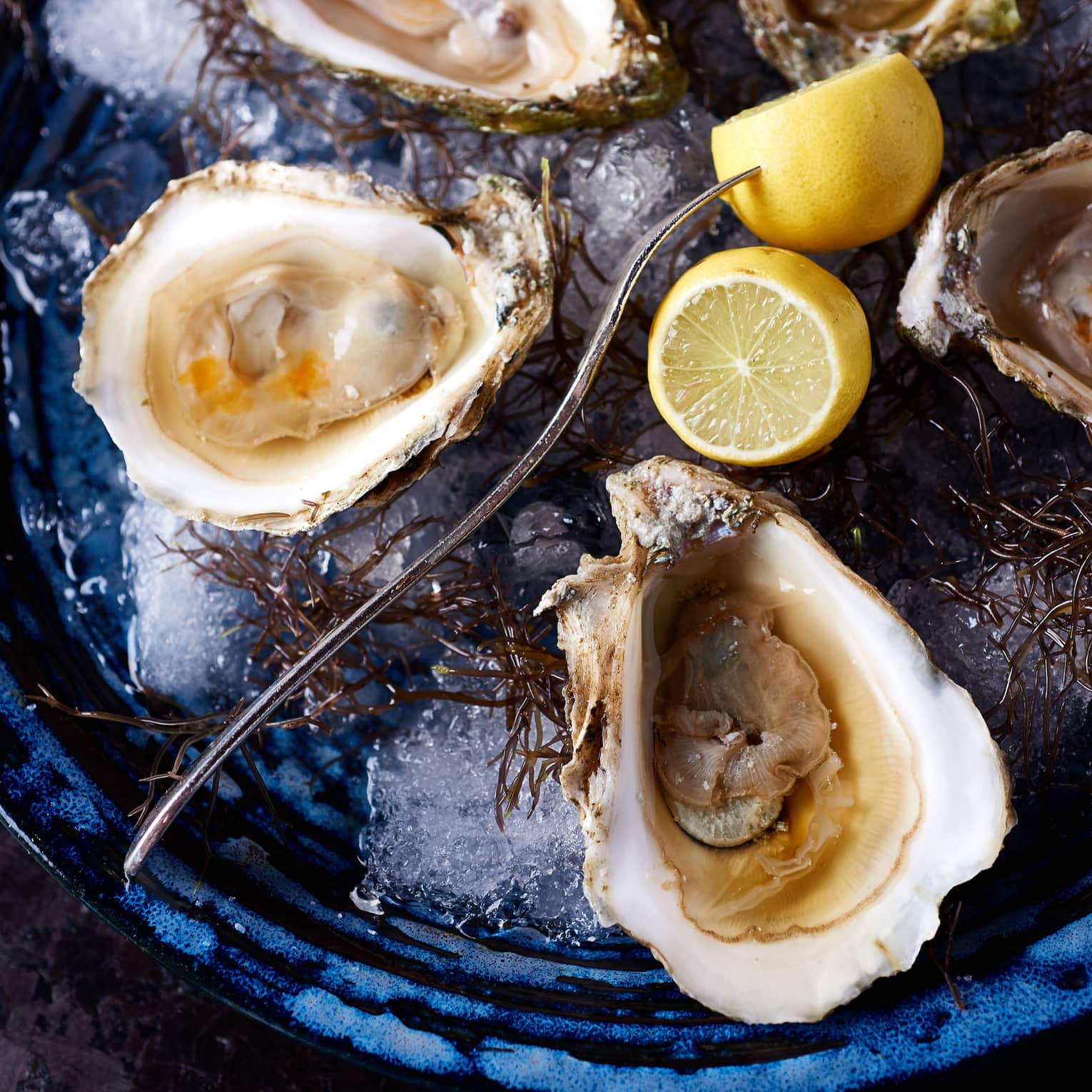 Oysters on a plate with a fork and lemons.