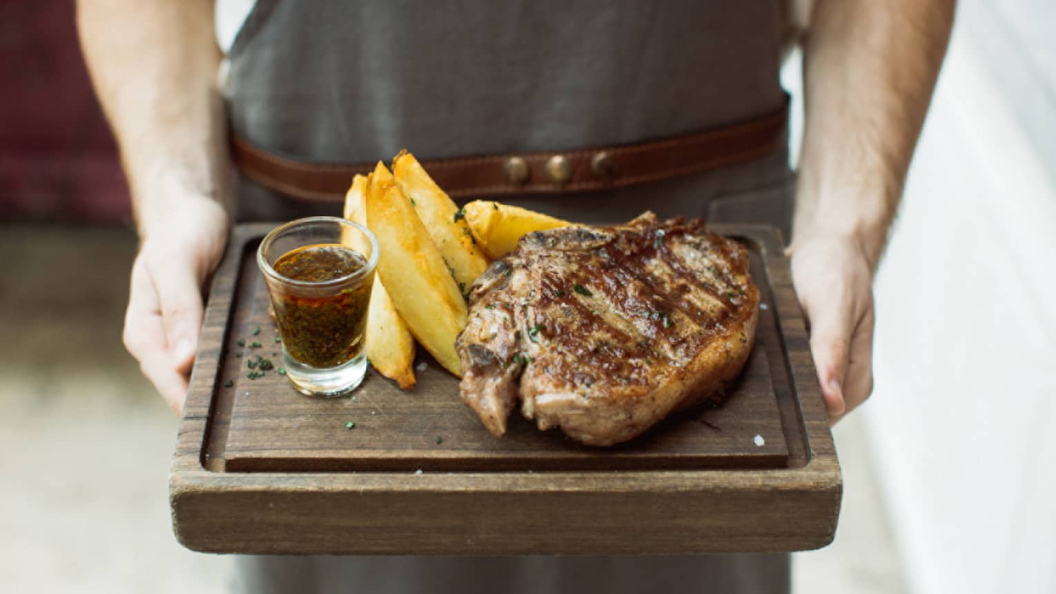 a 400-gram rib eye is served with chimichurri sauce and potato wedges