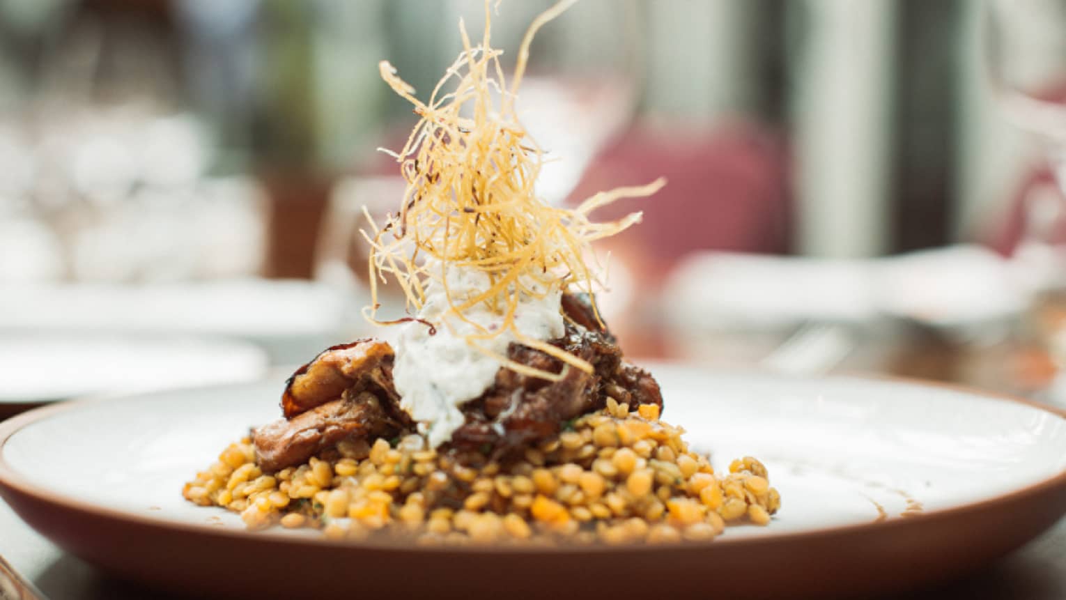 Braided lamb is served on top of Turkish lentils and topped with crispy onion