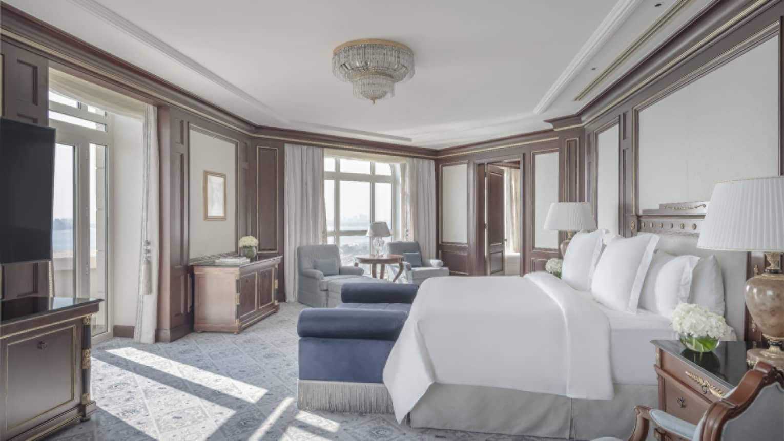 Elegant bedroom with king bed, blue bench, two walls of windows
