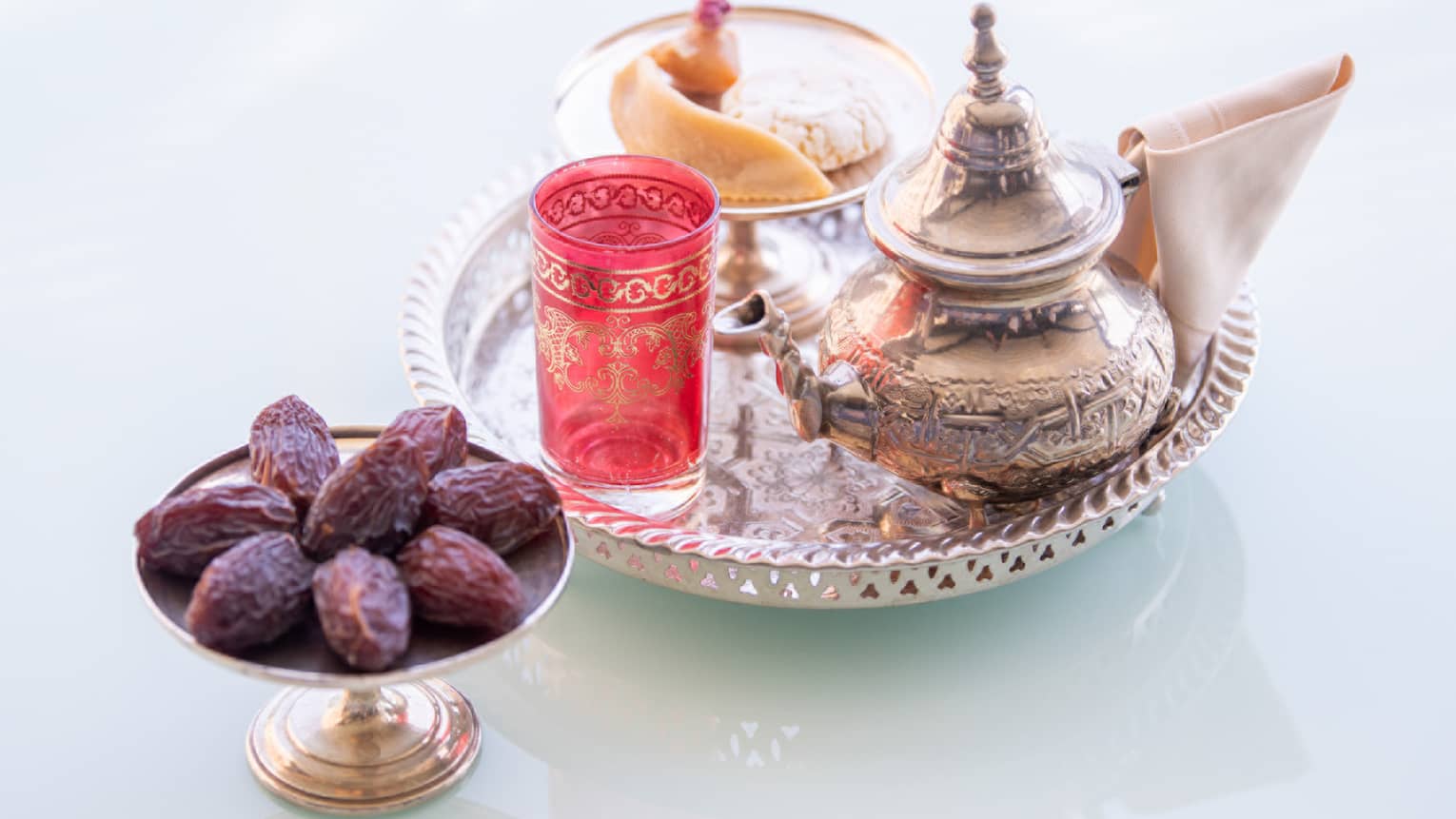 A silver platter of tea served with a plate of dates.