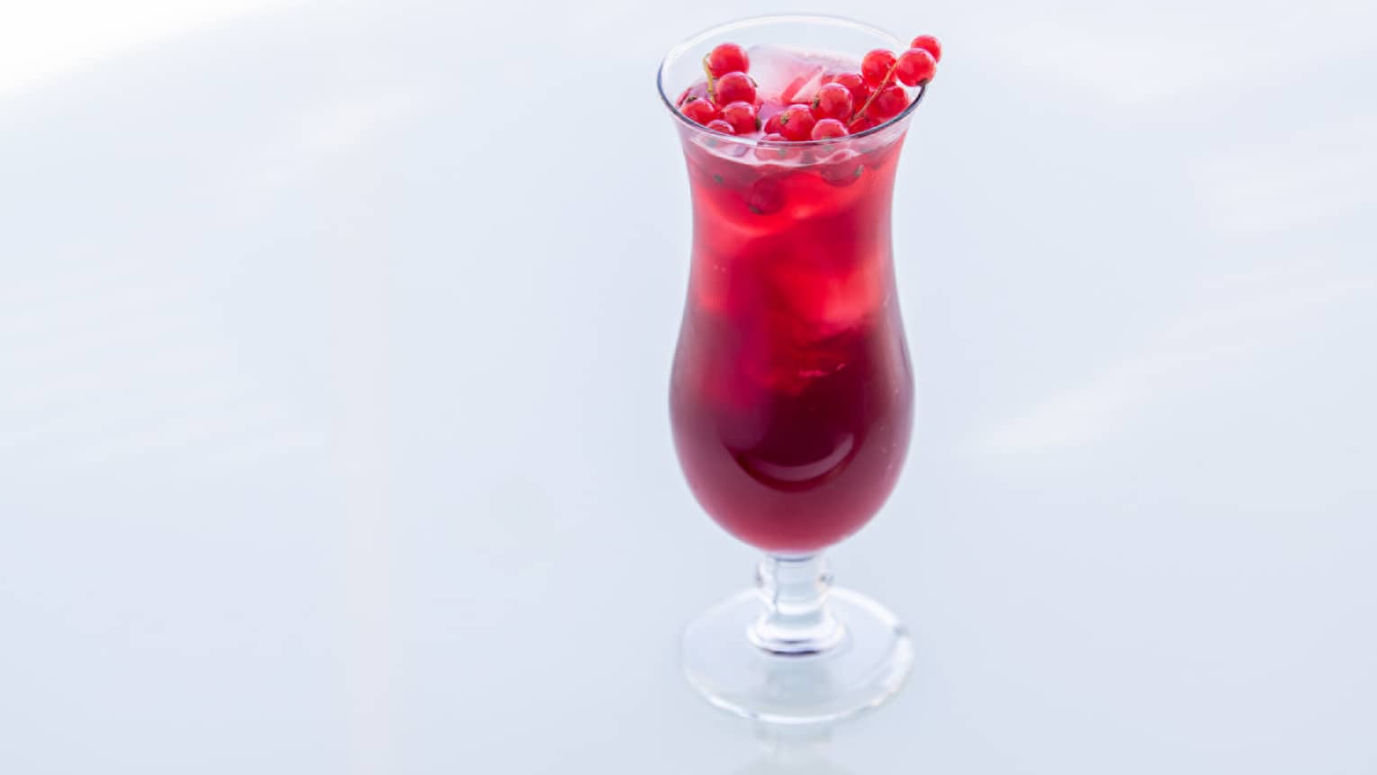 A burgundy coloured drink with hibiscus at the top.