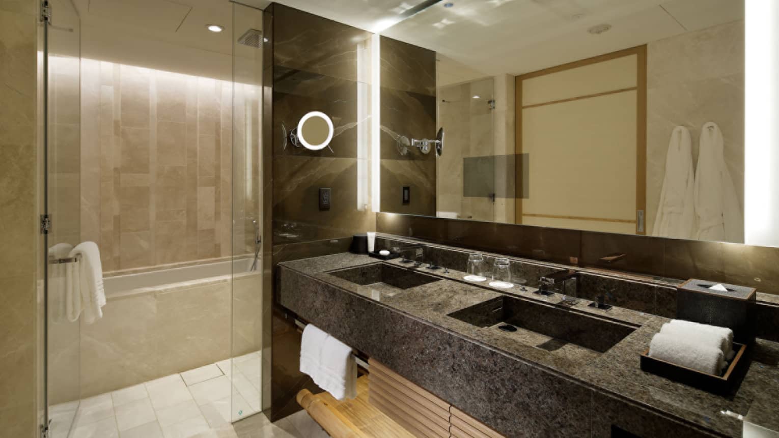 Luxury hotel bathroom with a double-sink vanity, large mirror and glass-enclosed shower