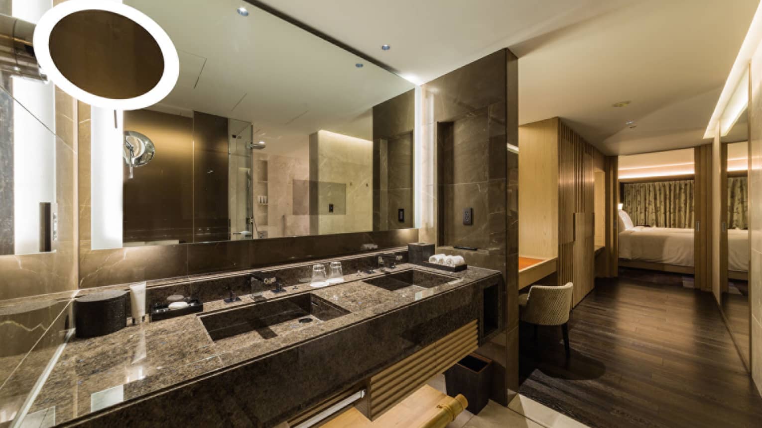 Luxury bathroom with a double-sink vanity, large mirror and ambient lighting, leading to the bedroom area at Four Seasons
