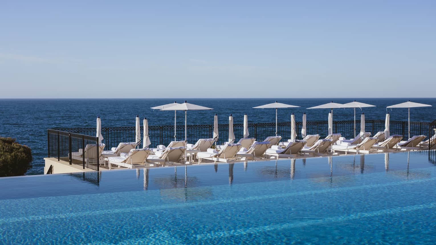 Sun loungers by infinity pool at luxury hotel 