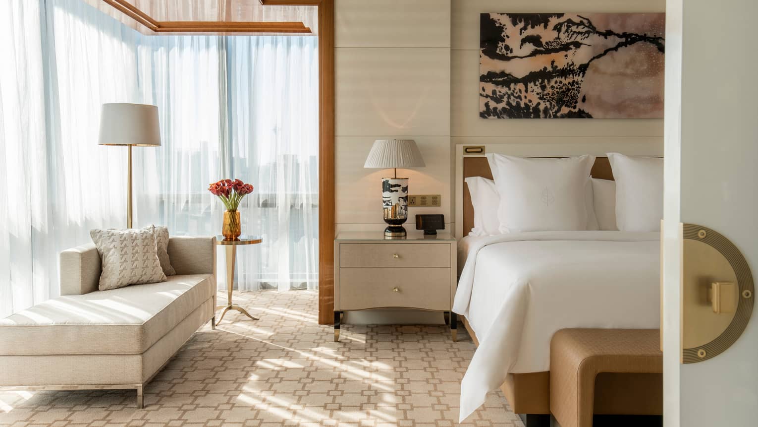White bed under modern pink-and-black art, corner window with sheer curtains, chaise