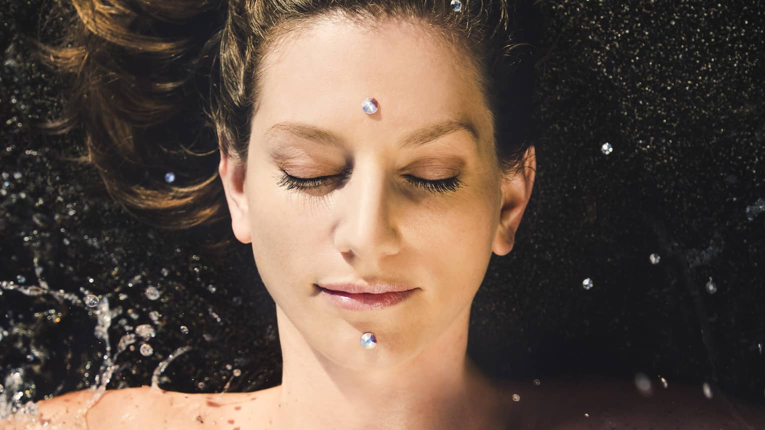 A woman enjoys a facial; two "black diamonds" are placed on forehead and chin
