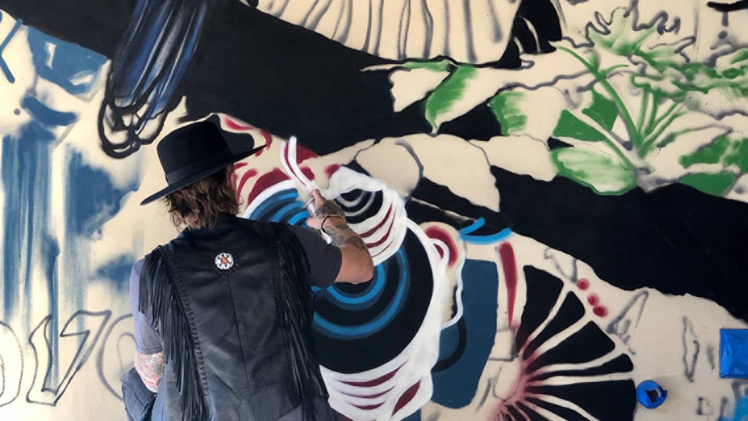 Graffiti artist paints a mural featuring a black crow