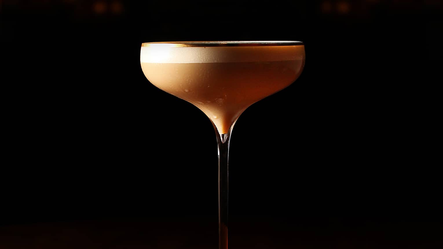 A tall glass with a light brown liquid.