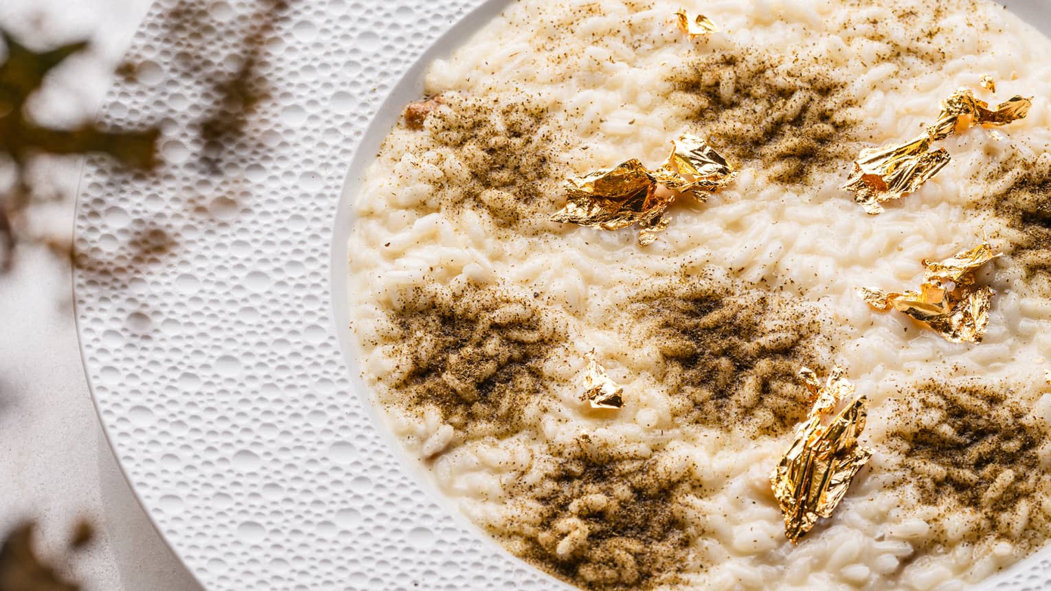 A creamy risotto dish garnished with gold flakes