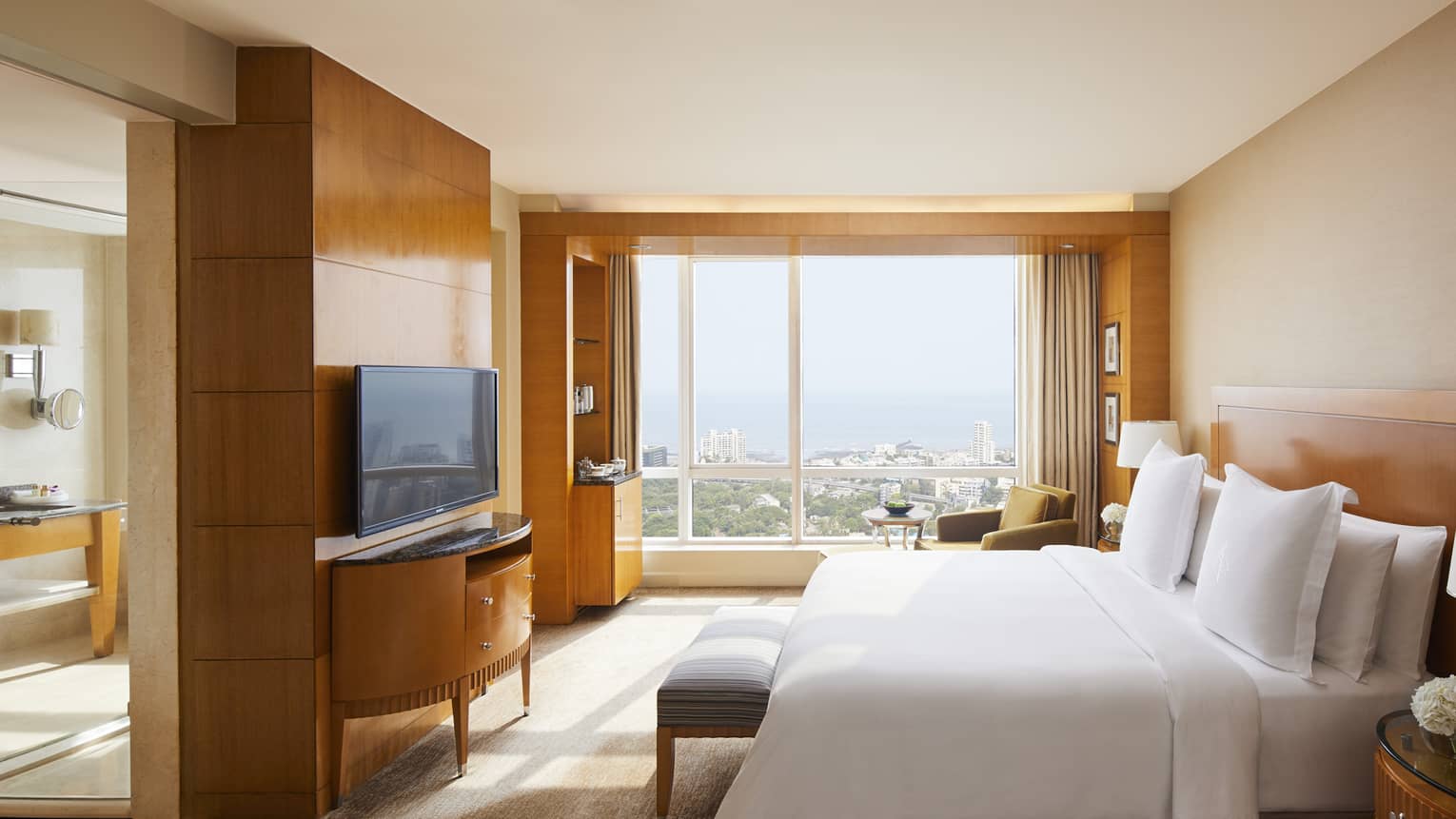 Deluxe room with natural light coming in and a view of the Mumbai skyline
