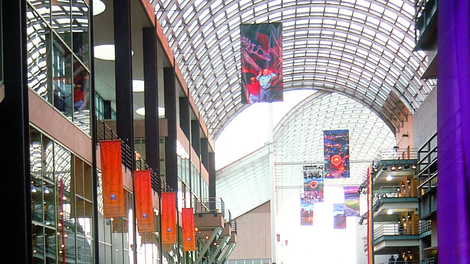 A large shopping and entertainment area with crowds of people walking along a large covered walkway.