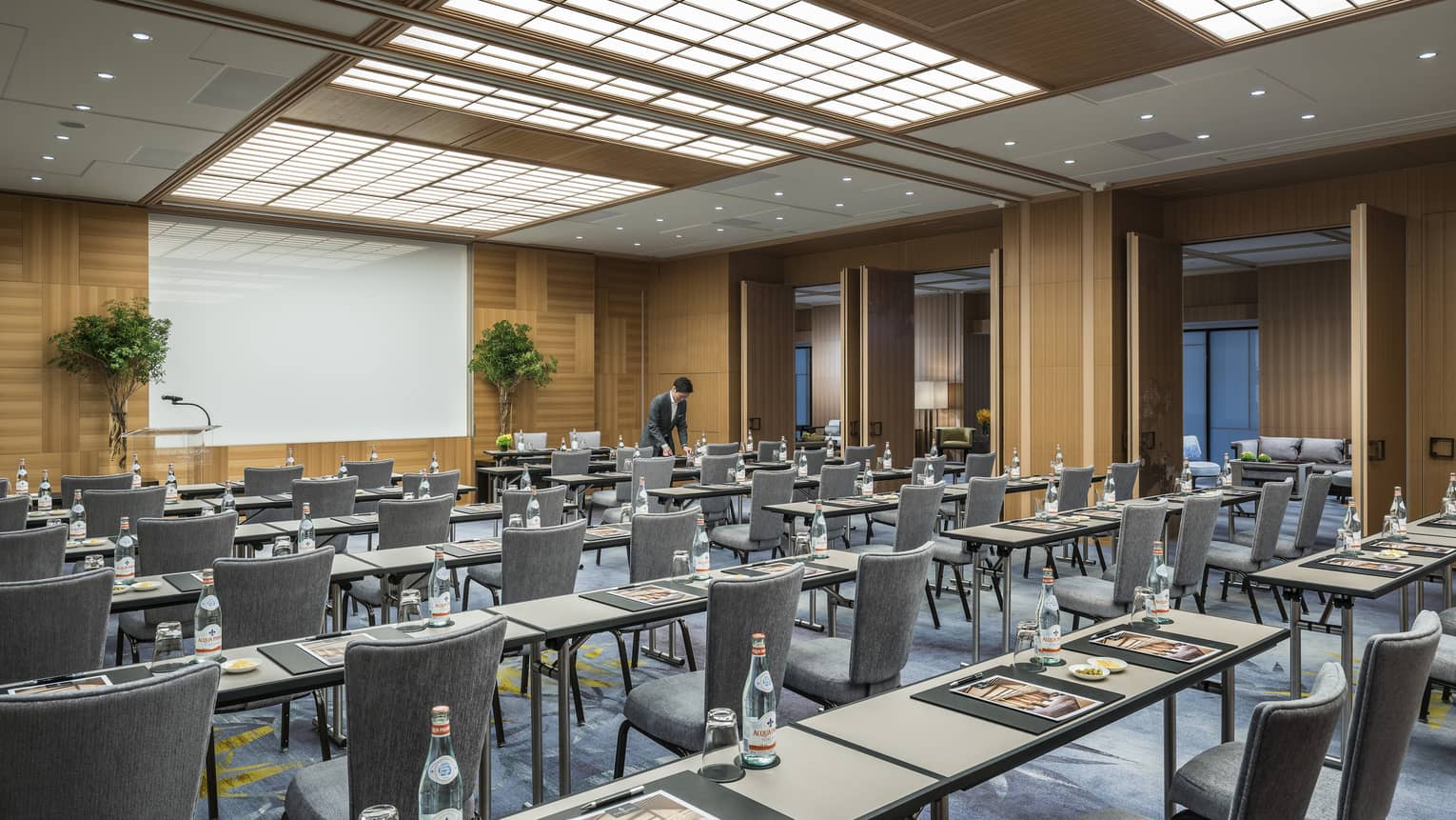 Conference event with rows of meeting tables, chairs facing screen