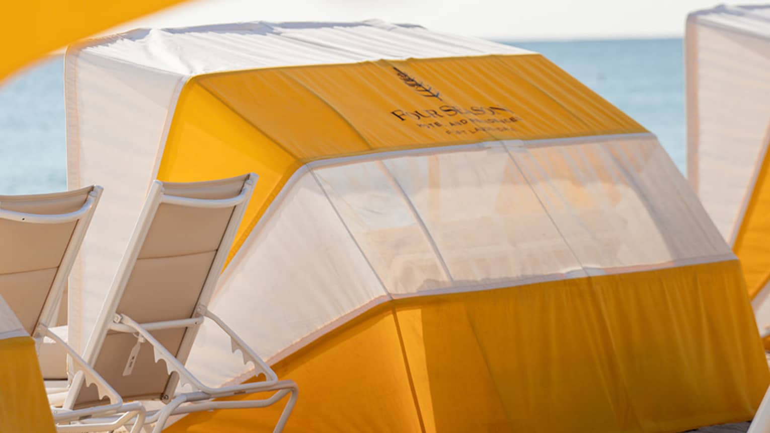 A daybed on the beach with lounge chairs