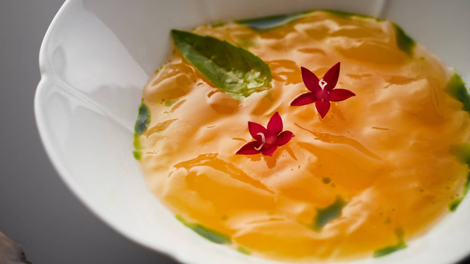 Tamarind coloured watermelon sorbet in a lily-shaped bowl, two tiny star-shaped deep pink flowers placed in the centre.