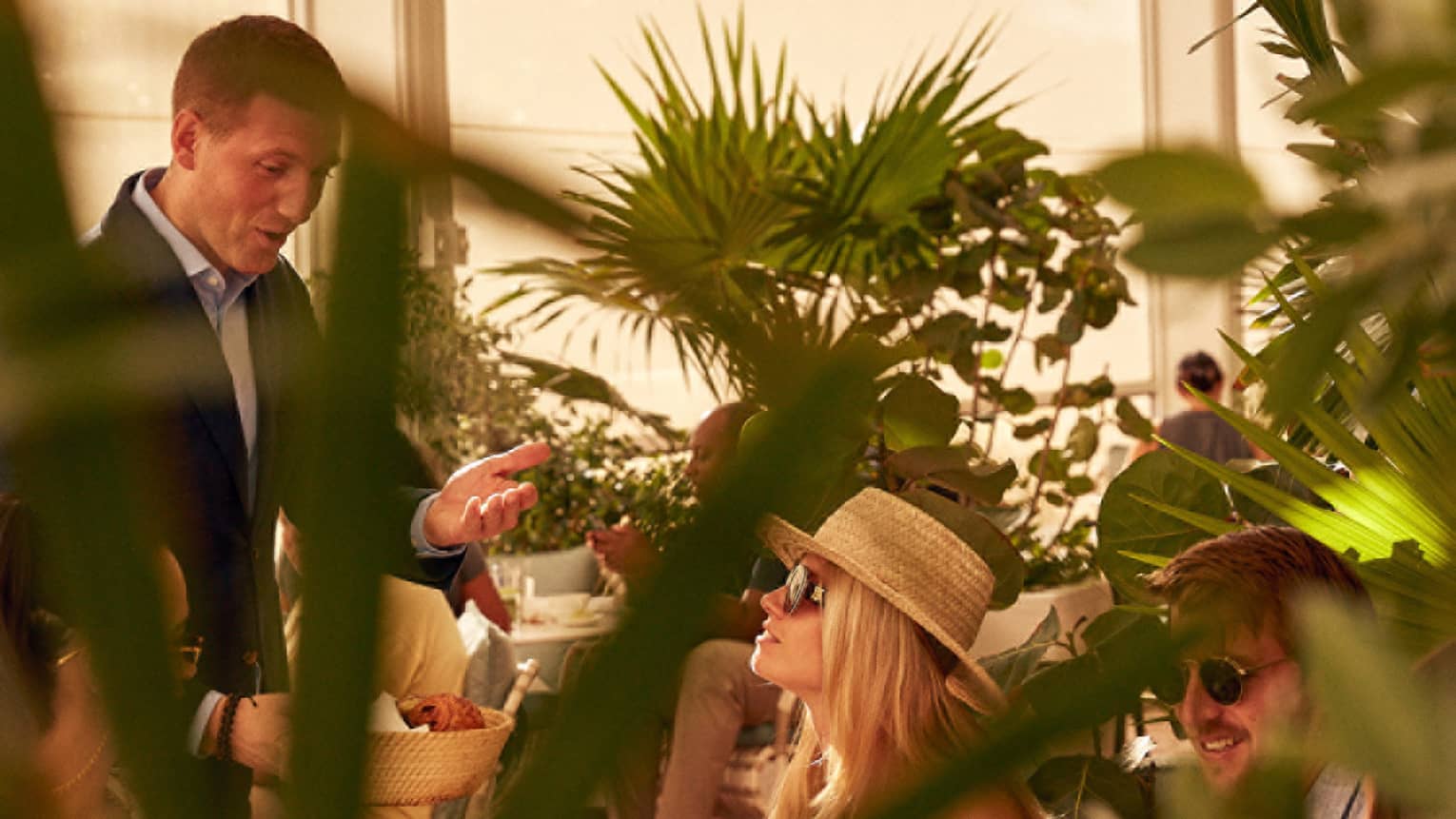 A woman being served food in a covered eating area with plants.
