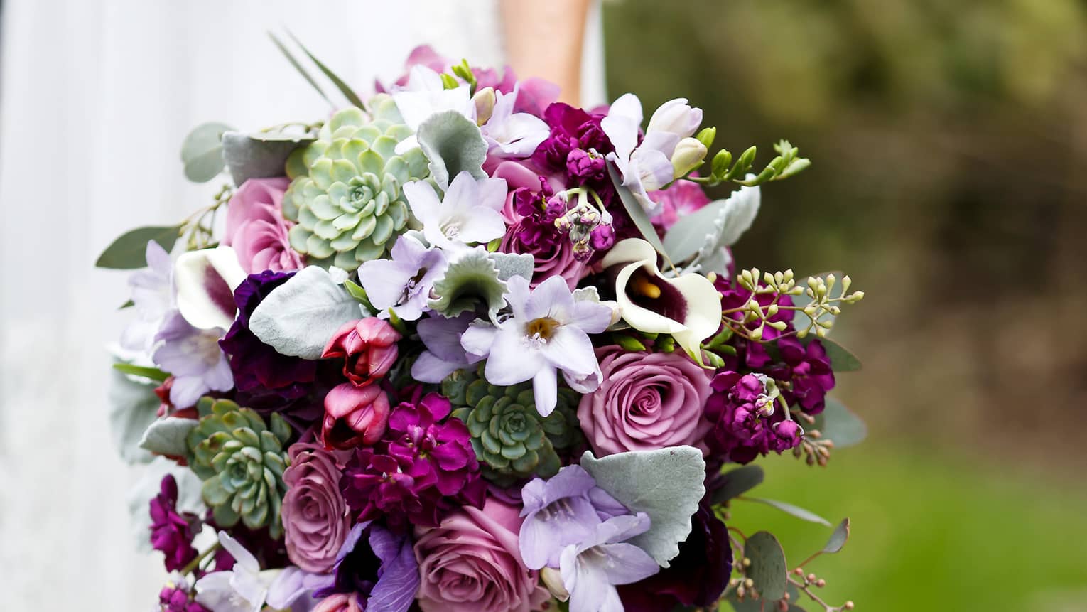 Bride holding floral wedding bouquet with purple flowers