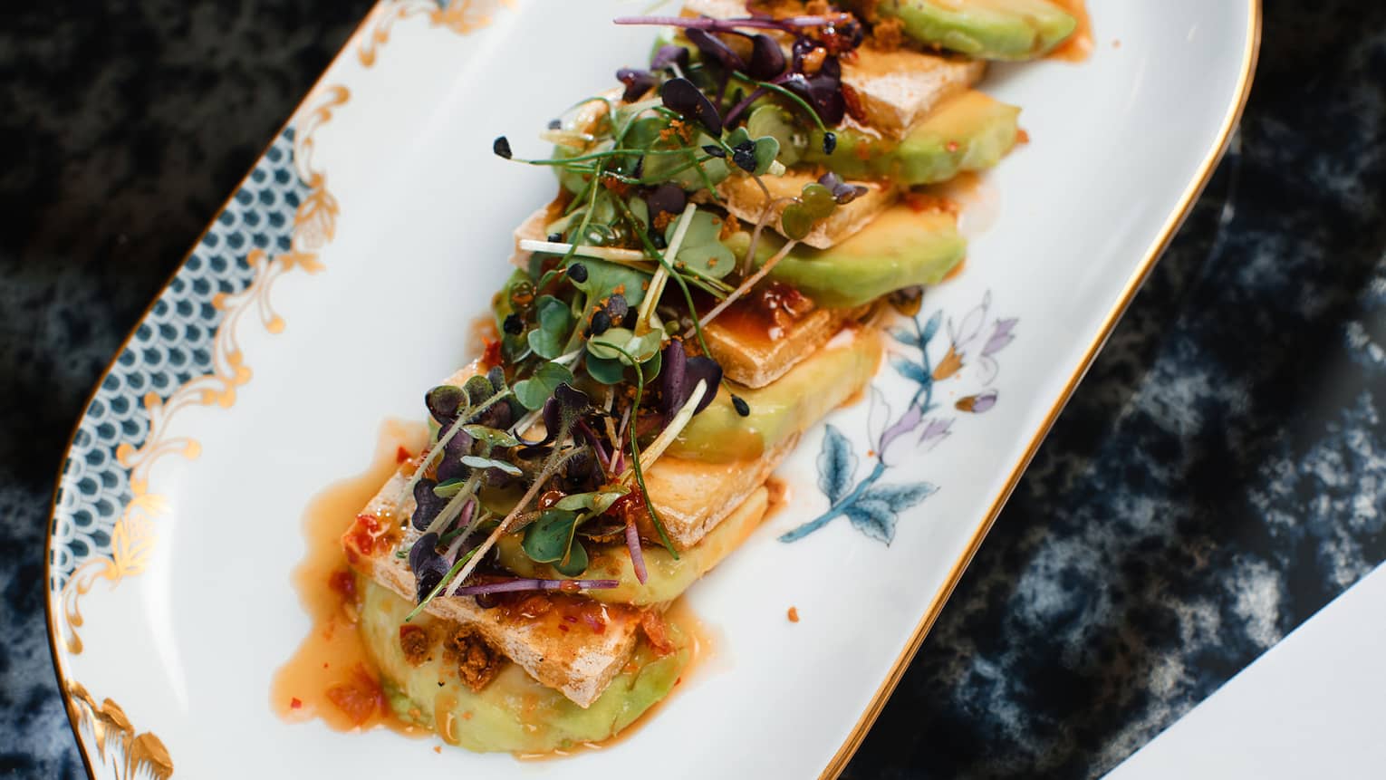 Fan of sliced Tofu & Avocado topped with Sesame-Soy Sauce and Micro-greens on oval porcelain platter