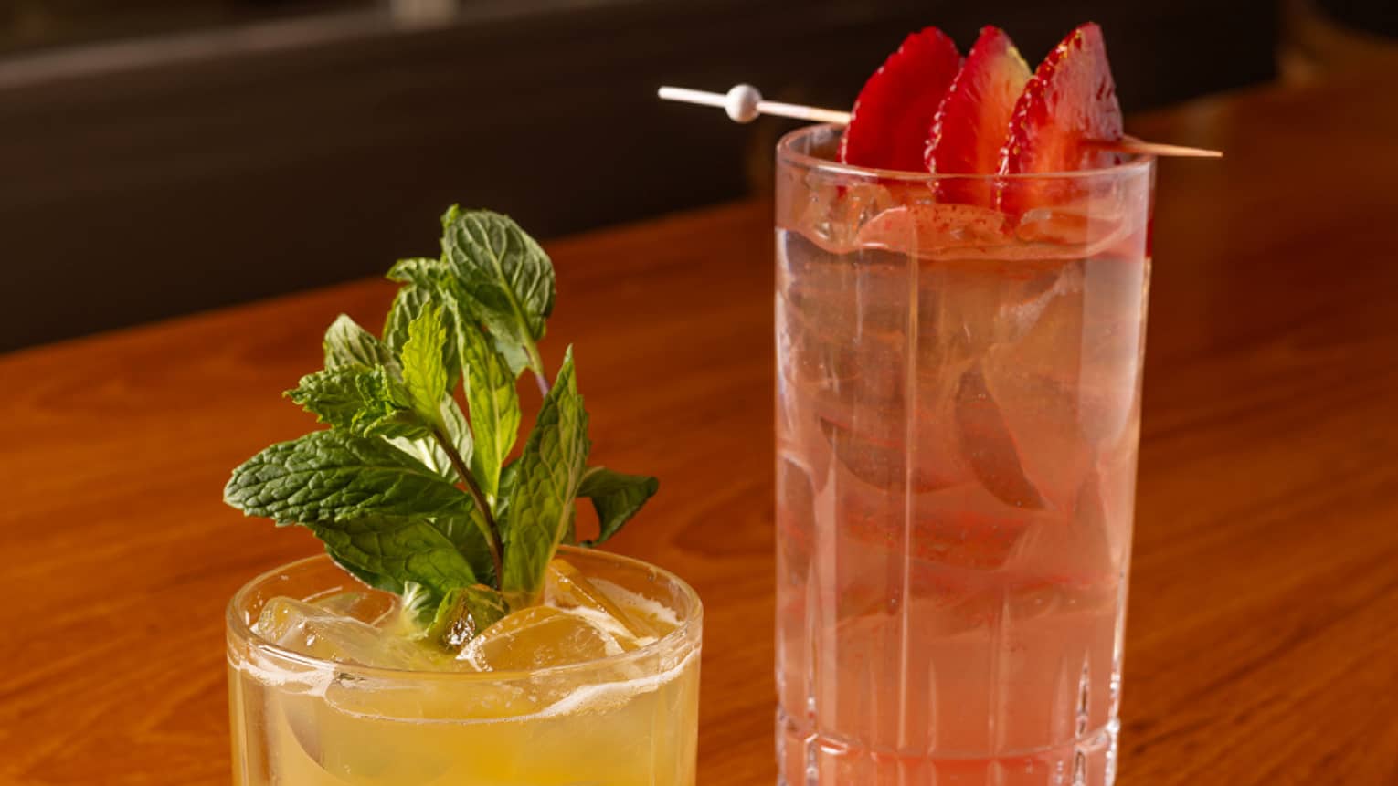 One yellow drink and one red drink placed beside each other on a dining table