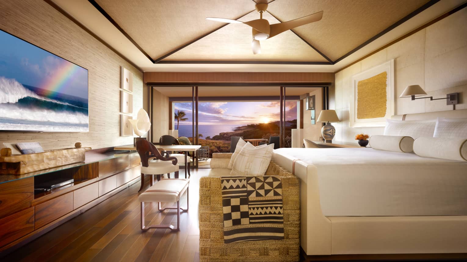 Partial Ocean-View Room bed, wicker sofa at foot with throw blanket, TV screen displaying waves, rainbow
