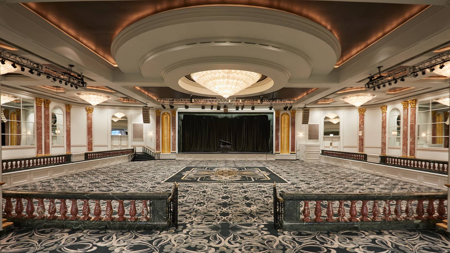 Spacious, empty, carpeted ballroom under large dome ceiling, crystal chandelier 