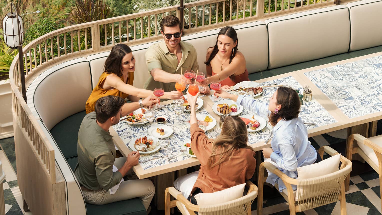Group of six people dining together at an outdoor restaurant table