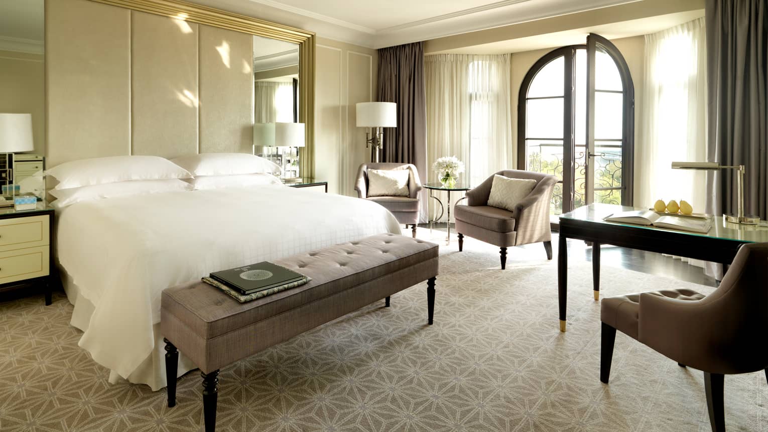Deluxe Caspian Room, books on plush bench at foot of bed, tall padded headboard and mirrors, chairs, French balcony
