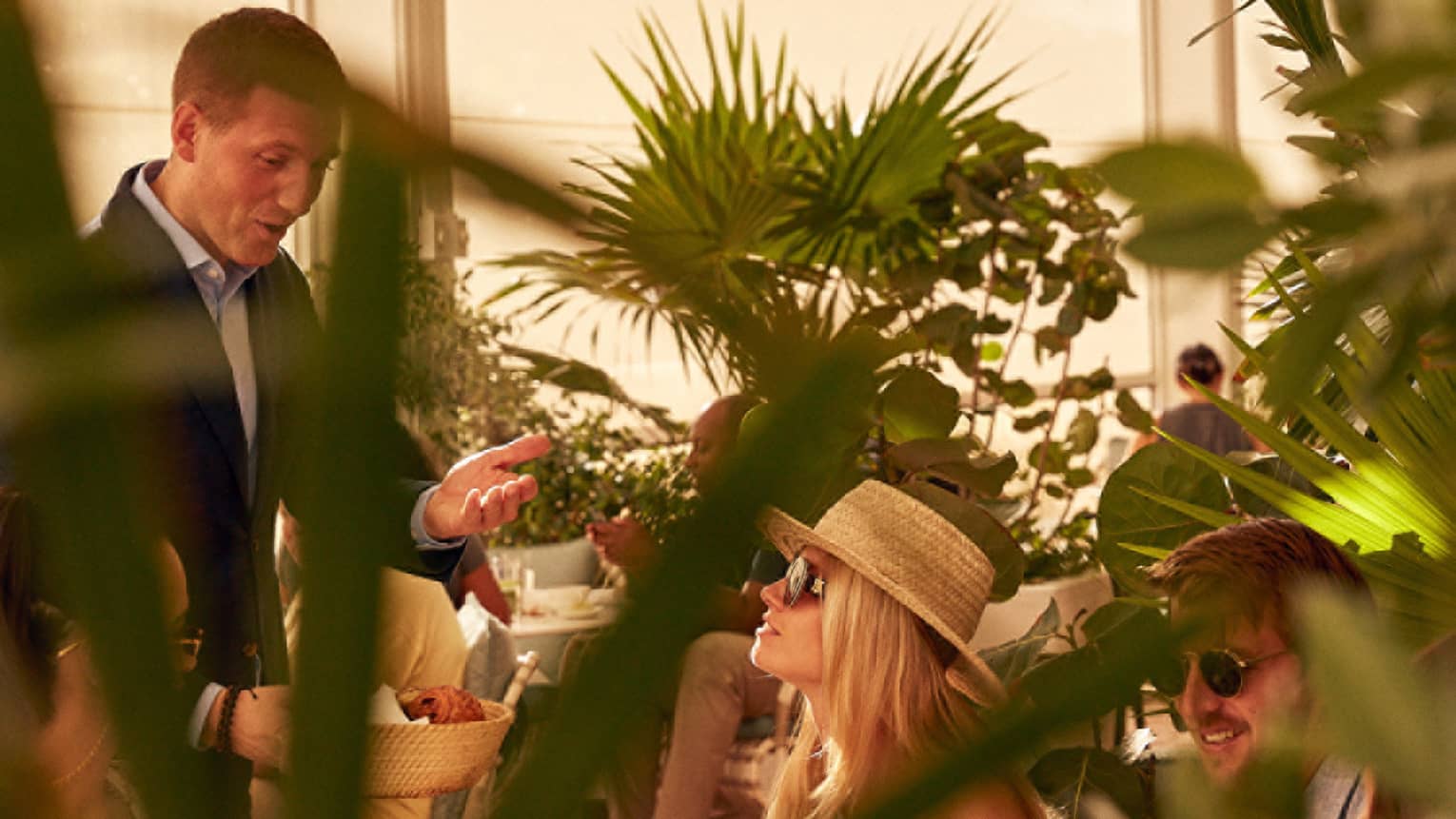A woman being served food in a covered eating area with plants.