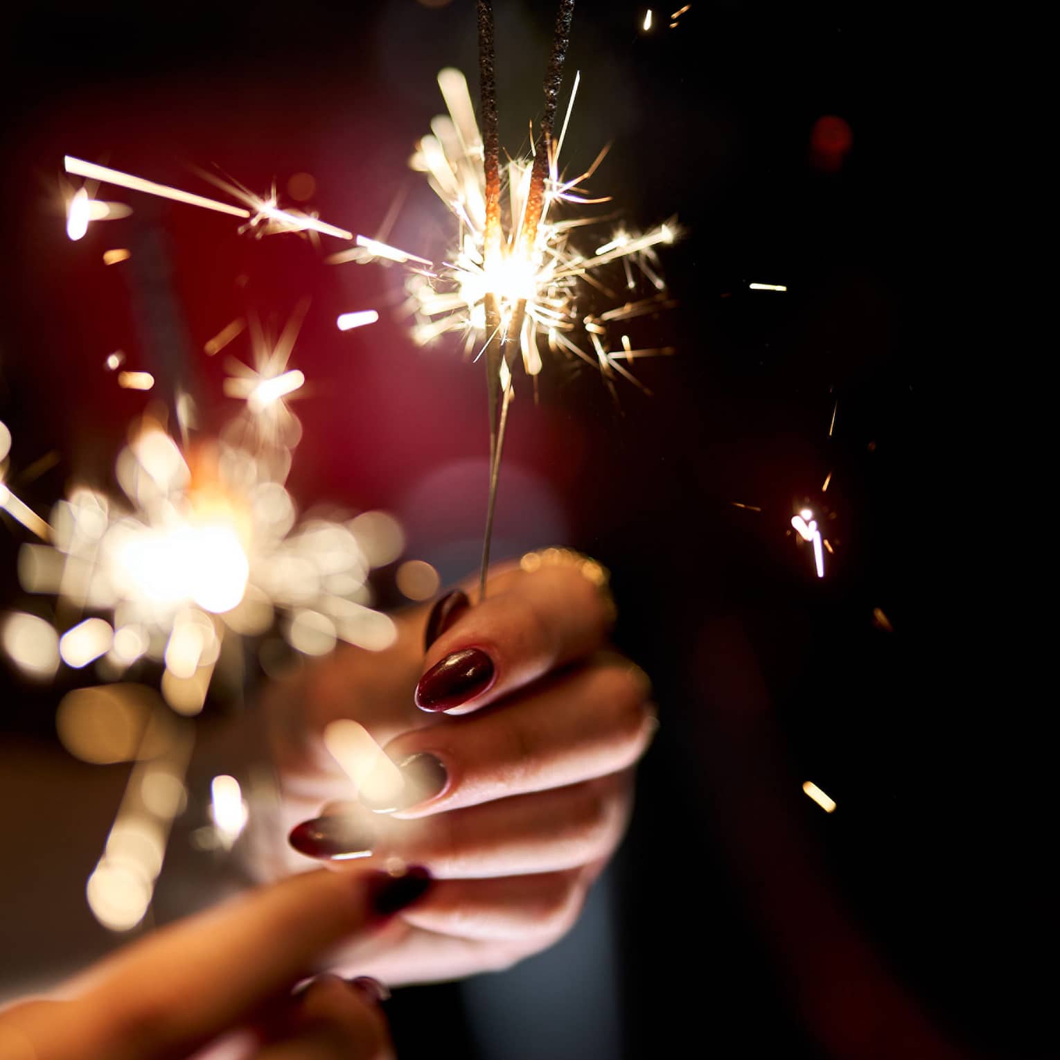 Hands holding a lit sparkler.