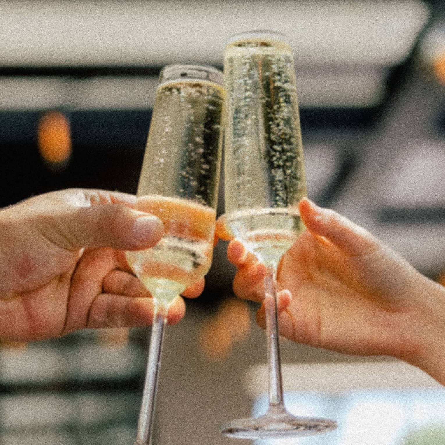 Two hands holding glasses of sparkling wine clink