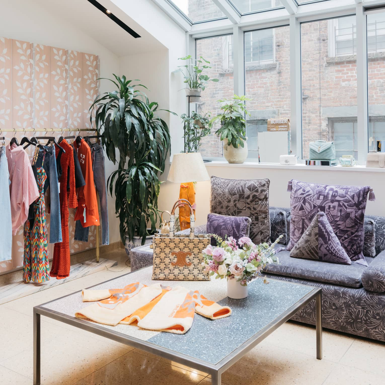 Clothes on a table and hanging near large windows.