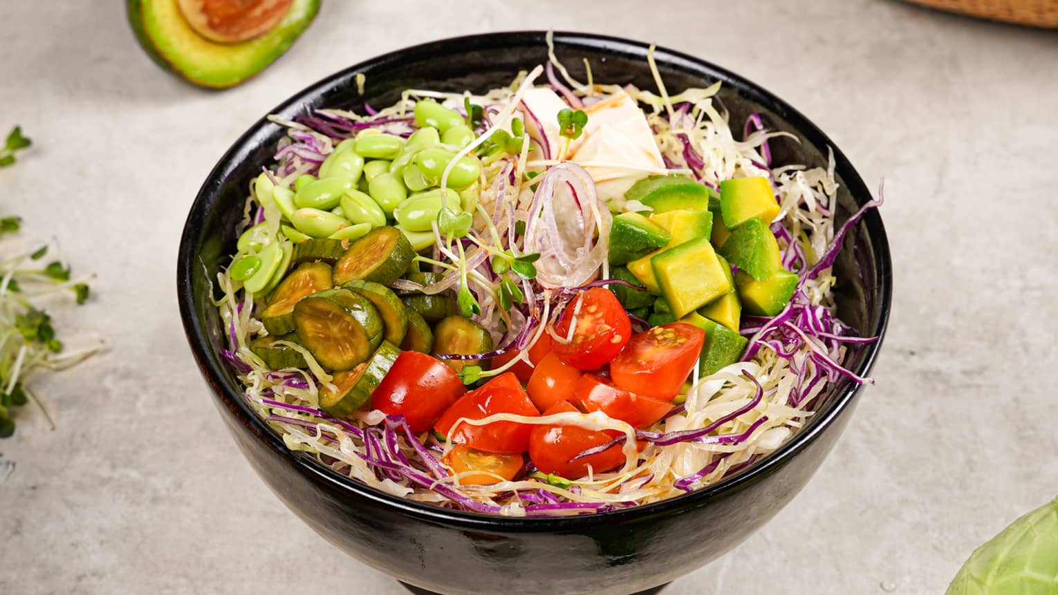 Poke bowl topped with colourful vegetables including tomatoes, edamame and avocado