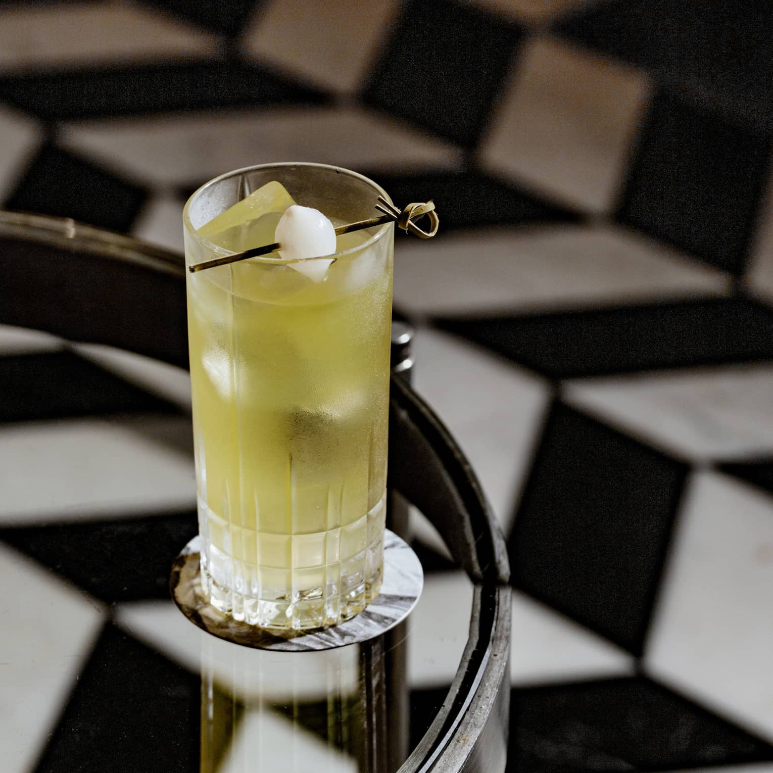 A yellow cocktail on a glass table.
