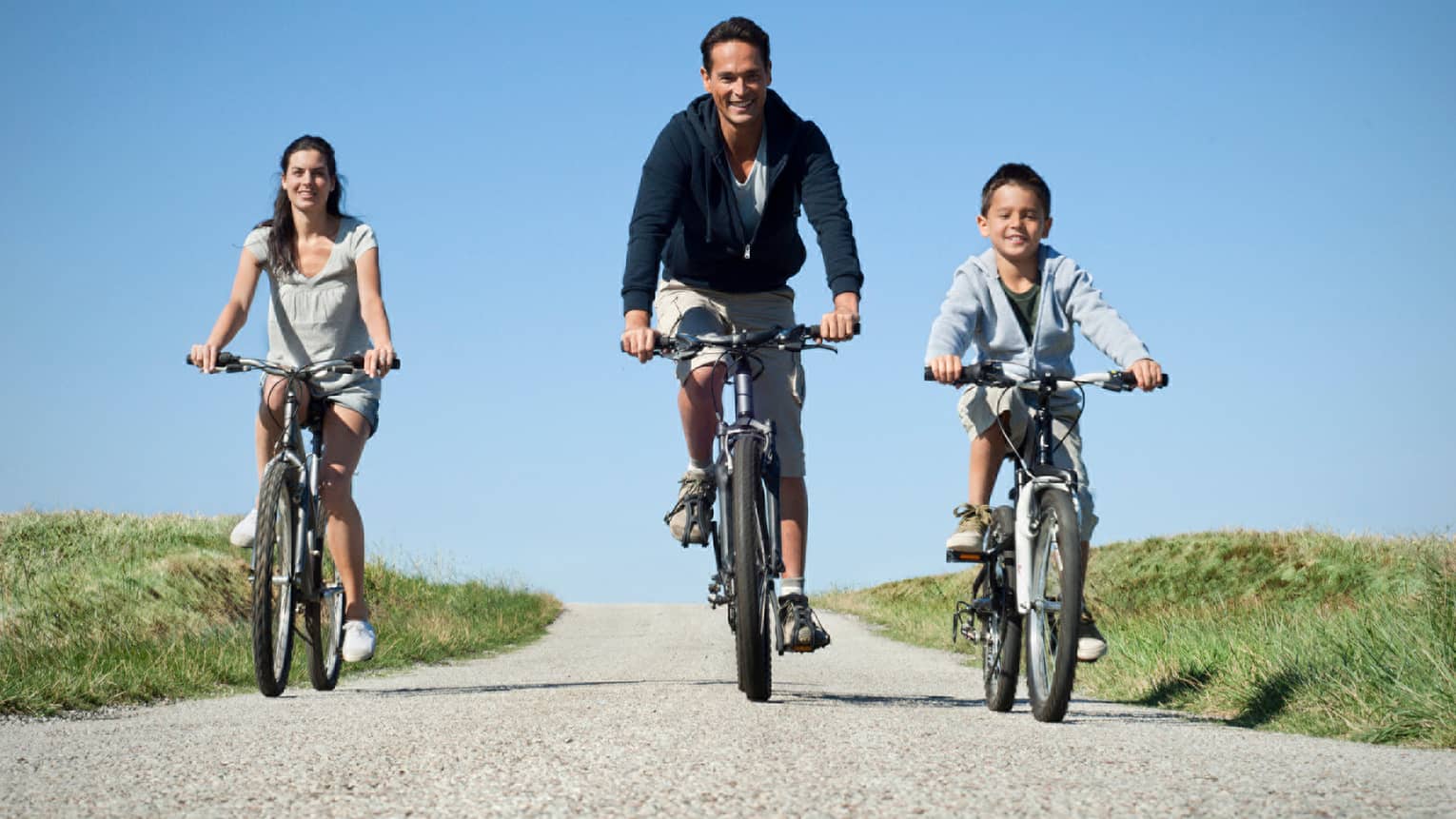 Family of three cycling on countryside pebble path